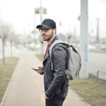 A fashionable young man in Budapest checking his smartphone on a busy street.